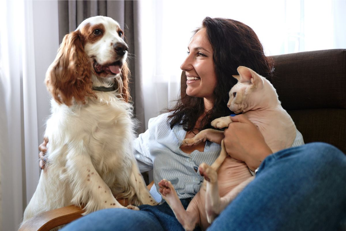 Lady sitting on couch with her dog and cat