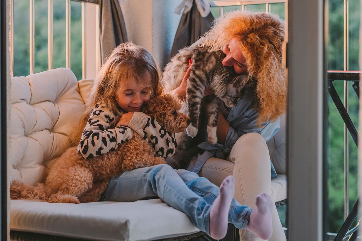Mum and daughter hugging a cat and dog