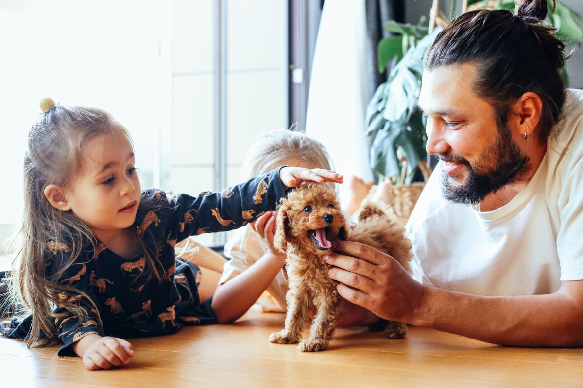 Father and daughters patting puppy